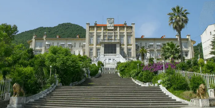 نمایی از ساختمان عظیم هتل قدیم رامسر و پله های احاطه شده با درختان و گل های رنگارنگ 52478558475754