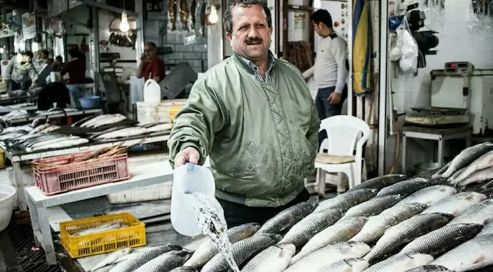 مردی در حال آب ریختن روی ماهی در بازار ماهی فروشان عباس آباد 48646454